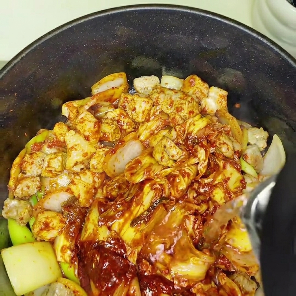Wasser wird in den Topf mit Kimchi und Fleisch gegossen, um den Garprozess zu beginnen.
