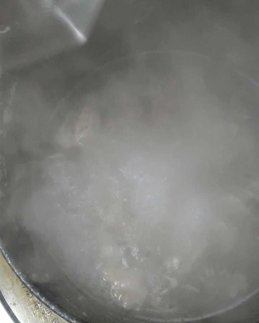 Klares Wasser wird in einen köchelnden Topf gegossen.