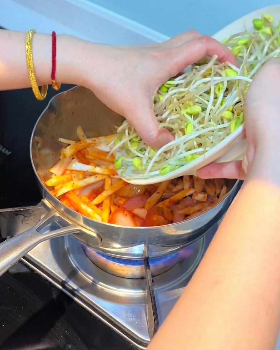 Frische Sojasprossen werden auf die Kimchi-Pilz-Mischung geschichtet.