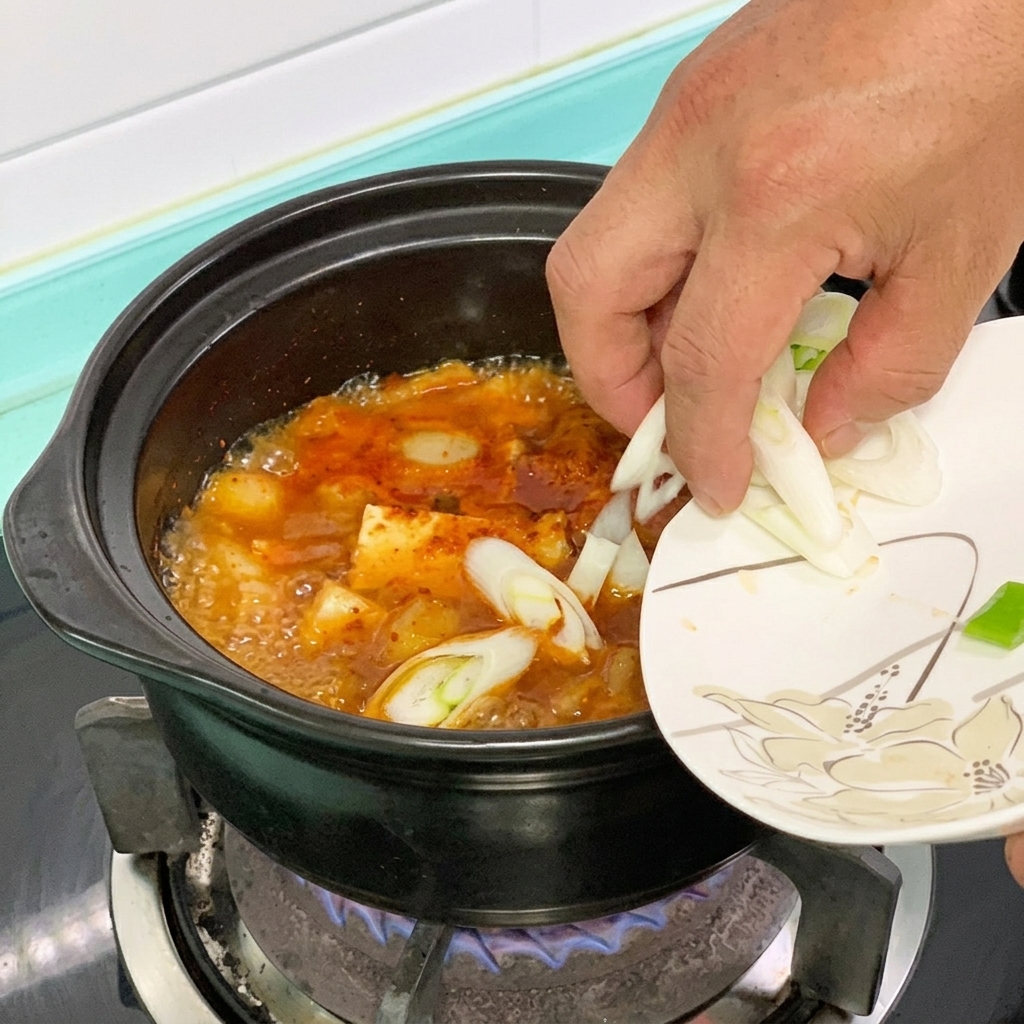 Grüne Chili und Frühlingszwiebeln werden in den Tofu-Eintopf gegeben.
