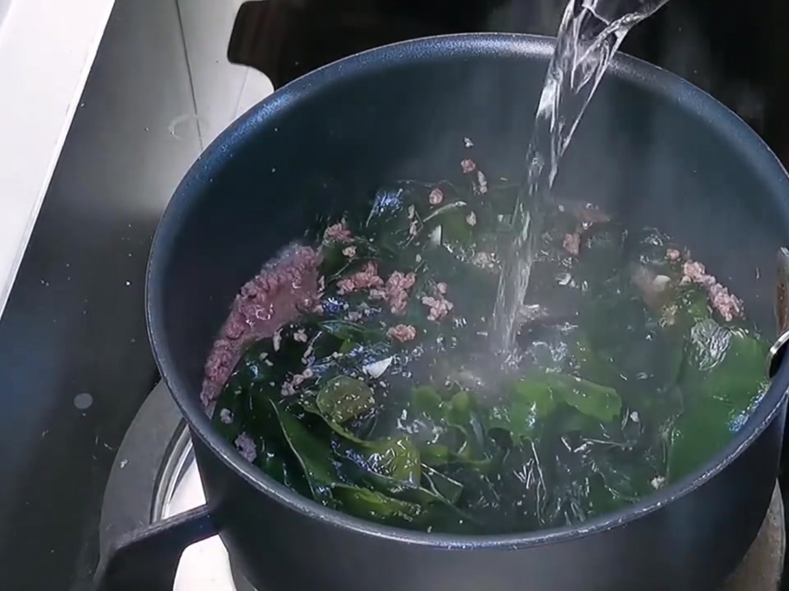 Frisches Wasser wird in den Topf über die Mischung aus Rindfleisch und Wakame gegossen.