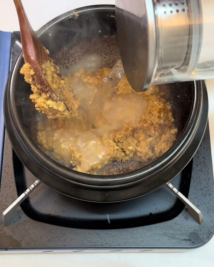 Wasser wird in den Topf über die Mischung aus Paste und Knoblauch gegossen.