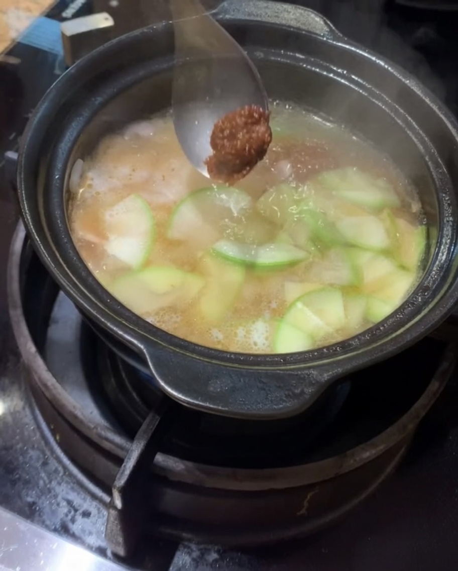 Koreanische Sojabohnenpaste und Chilipaste werden in die köchelnde Brühe gegeben.