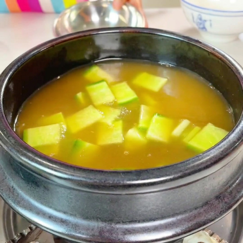 Gewürfelte Zucchini und geschnittene Pilze werden in den Topf gegeben.