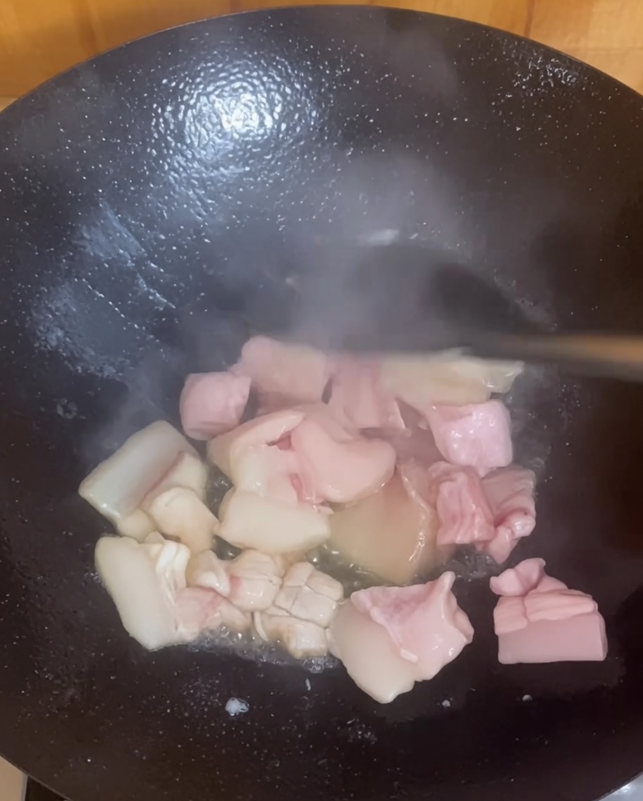 Schweinebauchstücke brutzeln und bräunen in einem heißen Wok.