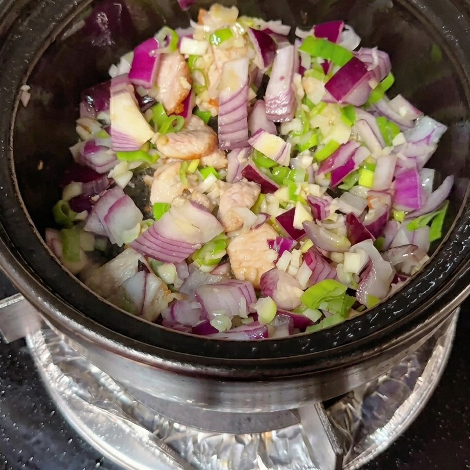 Koreanische Chilipaste und Chilipulver werden unter die Fleisch-Aromaten-Mischung gerührt.