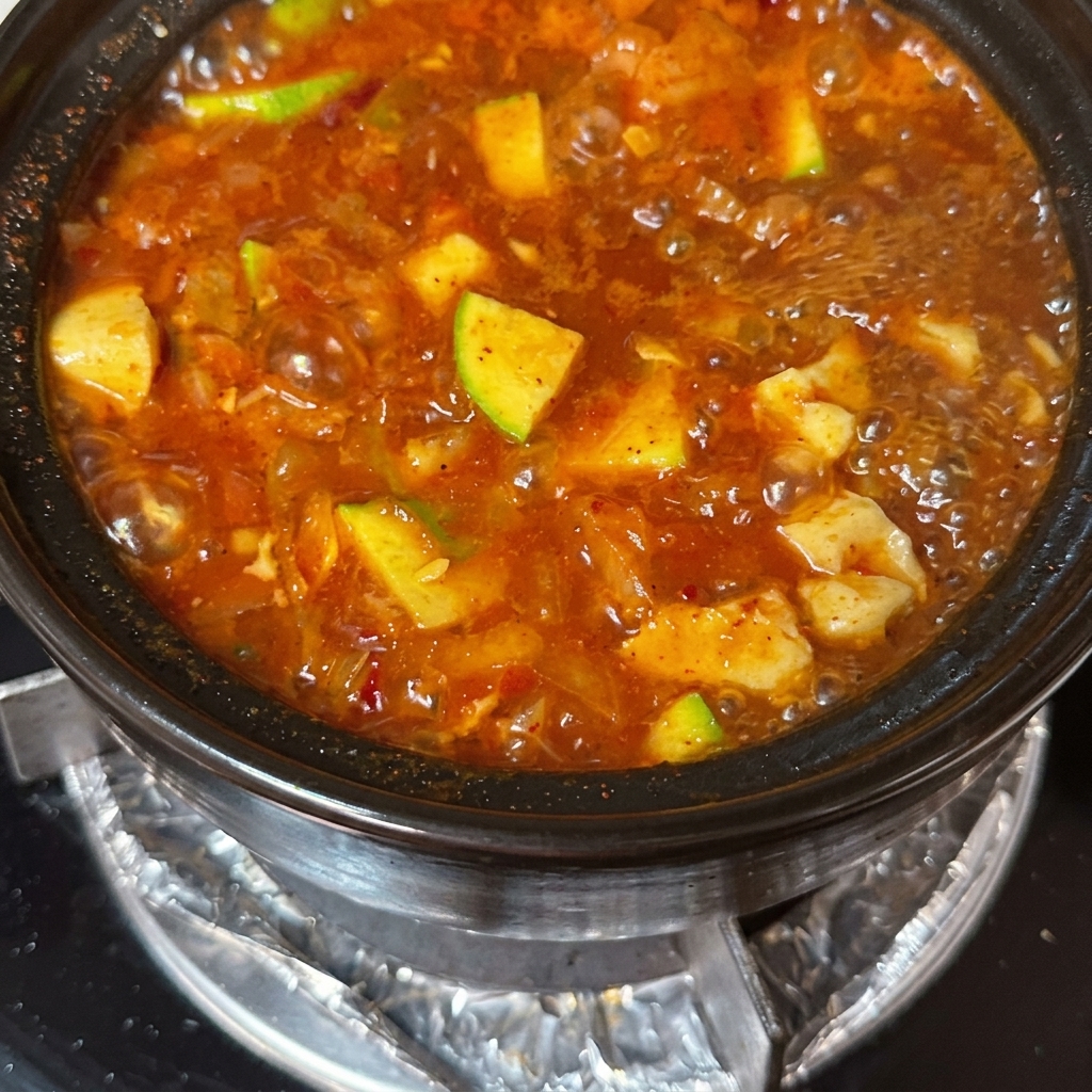 Dünne Rindfleischscheiben und rohe Eier werden in die köchelnde Suppe gegeben.