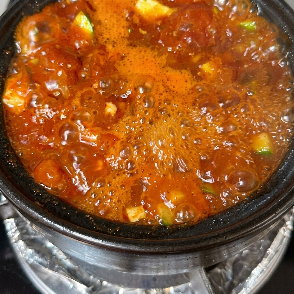 Ein fertiger Topf Tofu-Suppe, garniert mit geschnittenen Frühlingszwiebeln und Chiliringen.