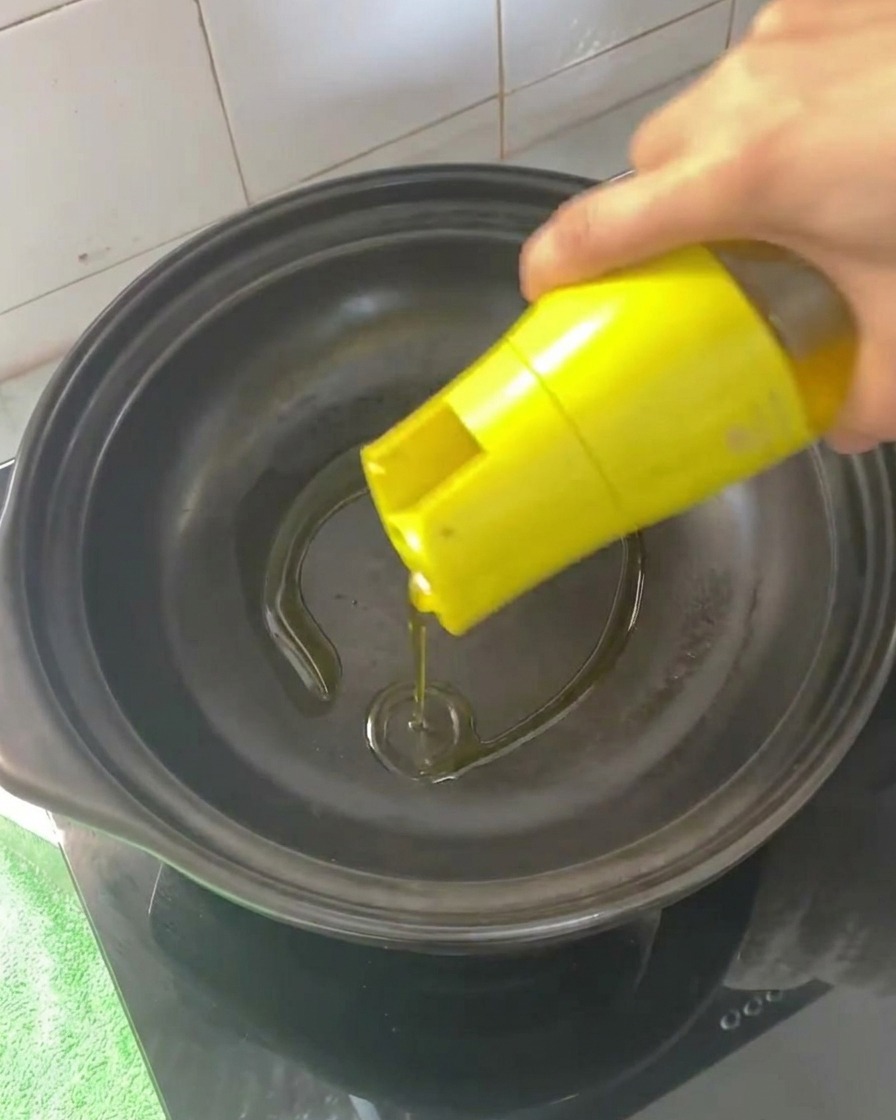 Speiseöl wird in einen leeren, erhitzten Tontopf gegossen.