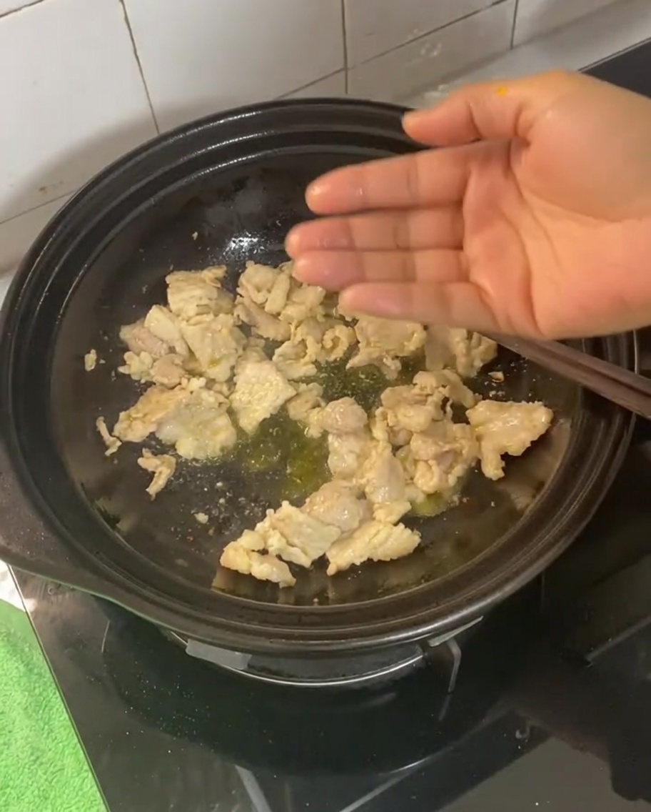 Ingwer, Knoblauch, Frühlingszwiebeln und getrocknete Chili werden zum angebratenen Schweinebauch gerührt.