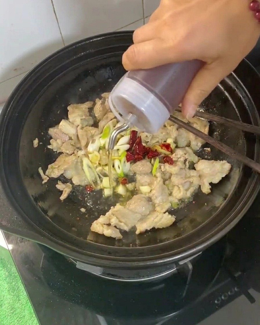 Kochwein wird in den Tontopf mit dem Fleisch und den Aromaten gegossen.