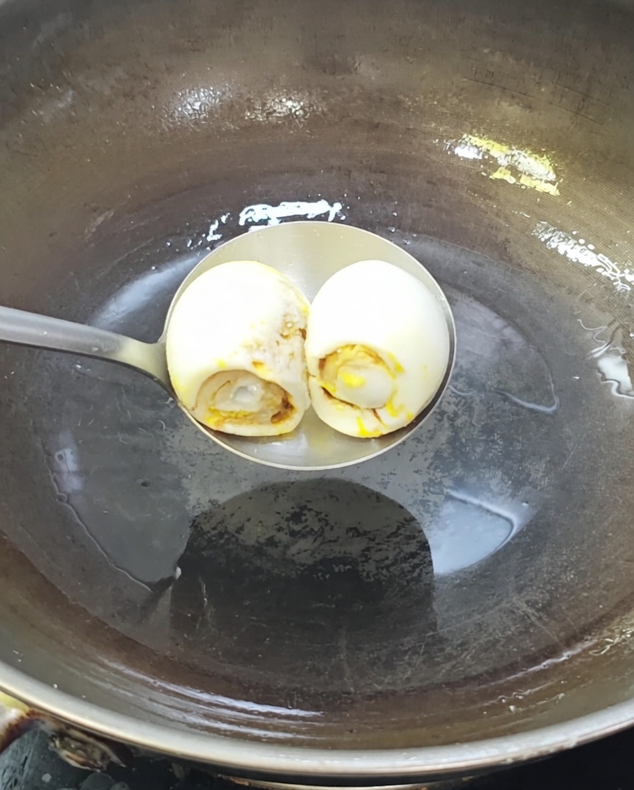 Zwei gesalzene Enteneier brutzeln in einem heißen Wok mit Öl.
