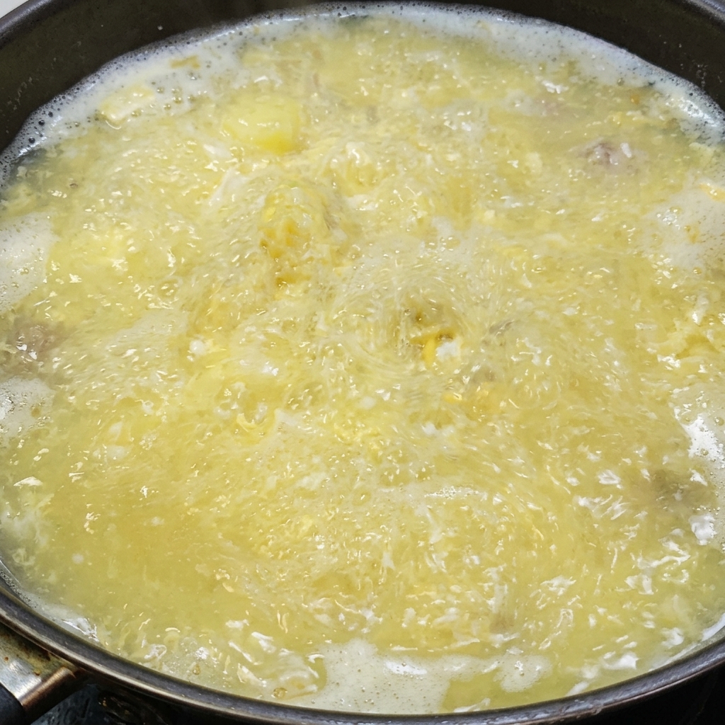 Salz und weißer Pfeffer werden in die köchelnde Suppe gestreut.