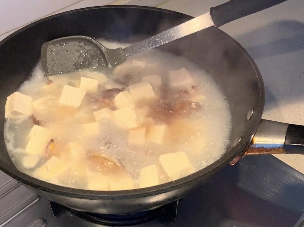Sojasauce wird in die köchelnde Suppe eingeträufelt.