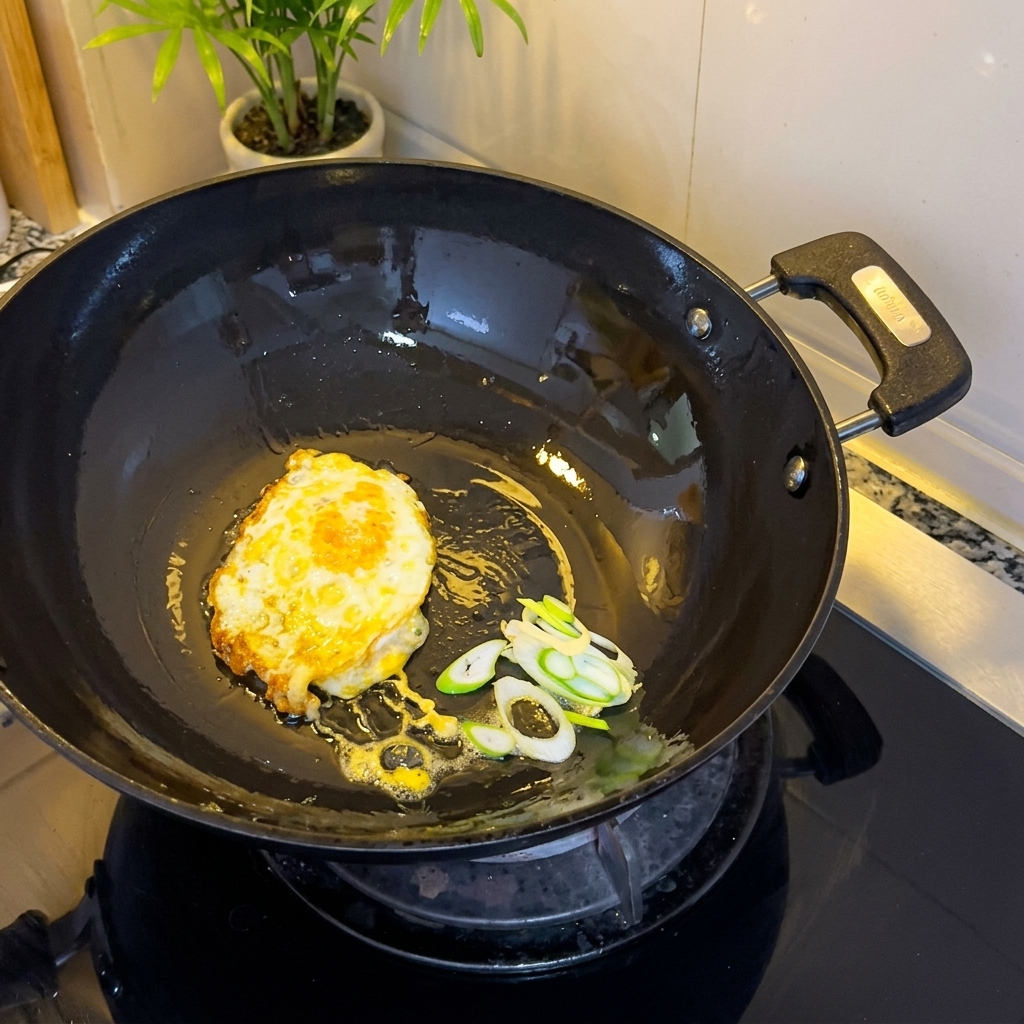 Gebratenes Ei und gehackte Frühlingszwiebeln brutzeln im Wok.
