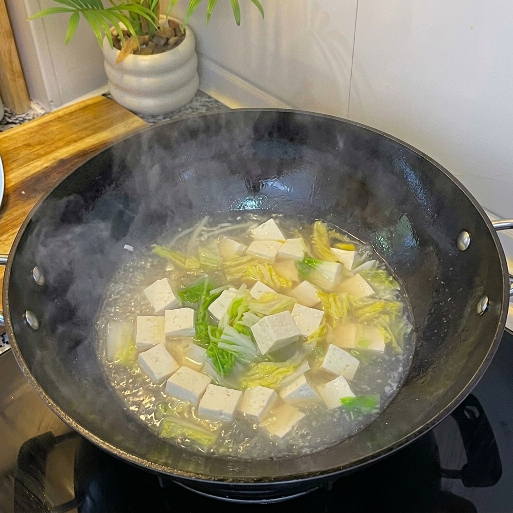 Frische weiße Muscheln werden zur köchelnden Suppe mit Tofu und Ei gegeben.