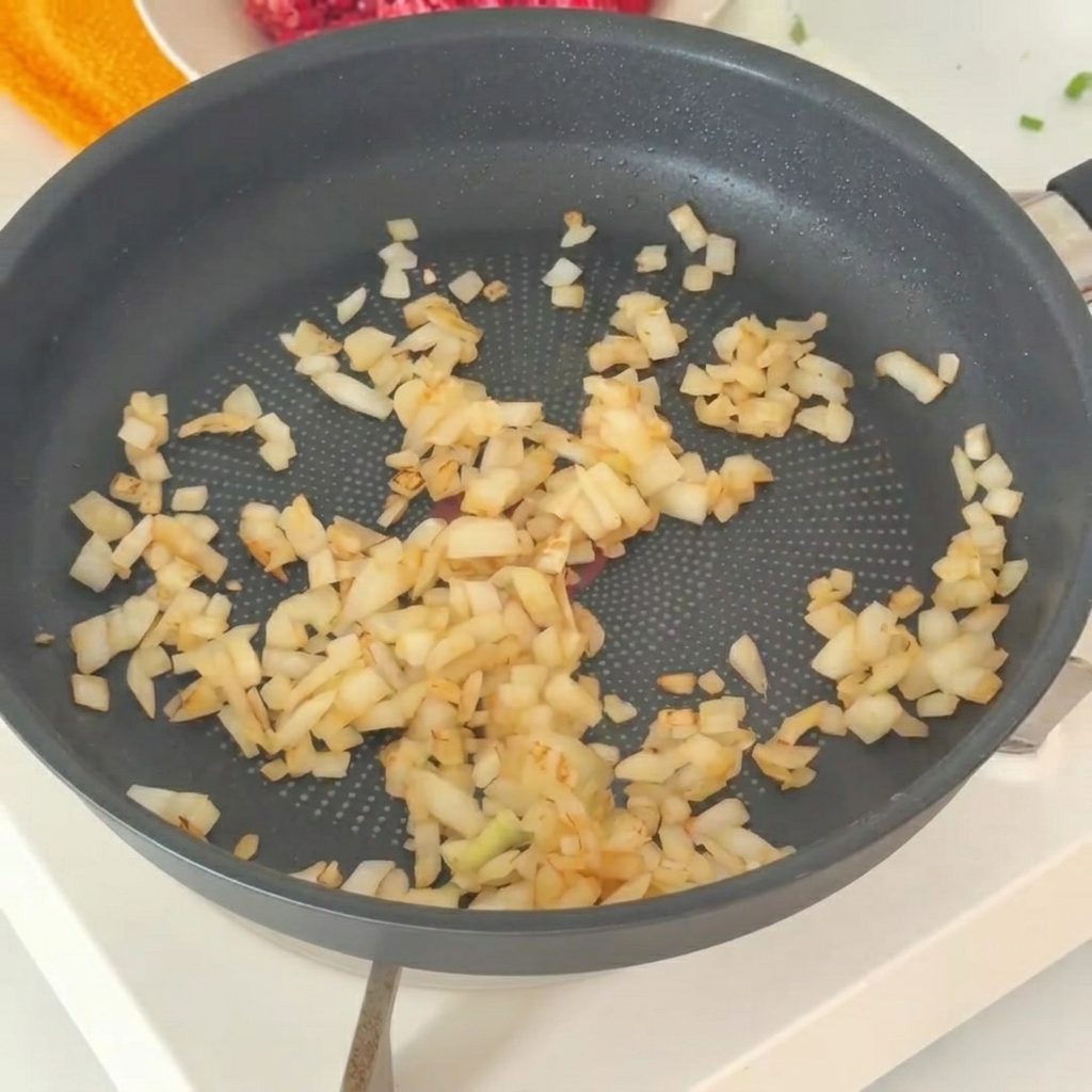Die angedünsteten Zwiebeln werden in eine Schüssel mit frischem Rinderhackfleisch gegeben.
