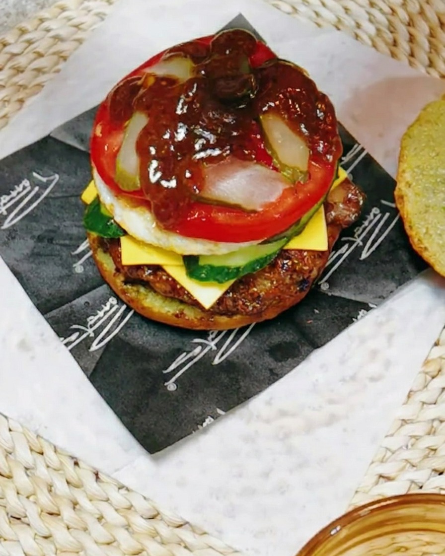 Nahaufnahme des Burgers, der mit einer dunklen, würzigen Teriyaki-Sauce mit einem Spritzer Zitronensaft beträufelt wird.