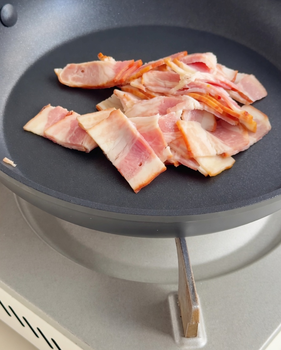 Speckstücke braten in einer Pfanne, bis sie knusprig und goldbraun sind.