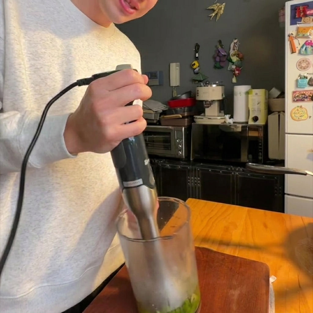 Ein Stabmixer püriert gegarten Spargel und Zwiebeln in einem Glasbehälter bis zur Feinheit.