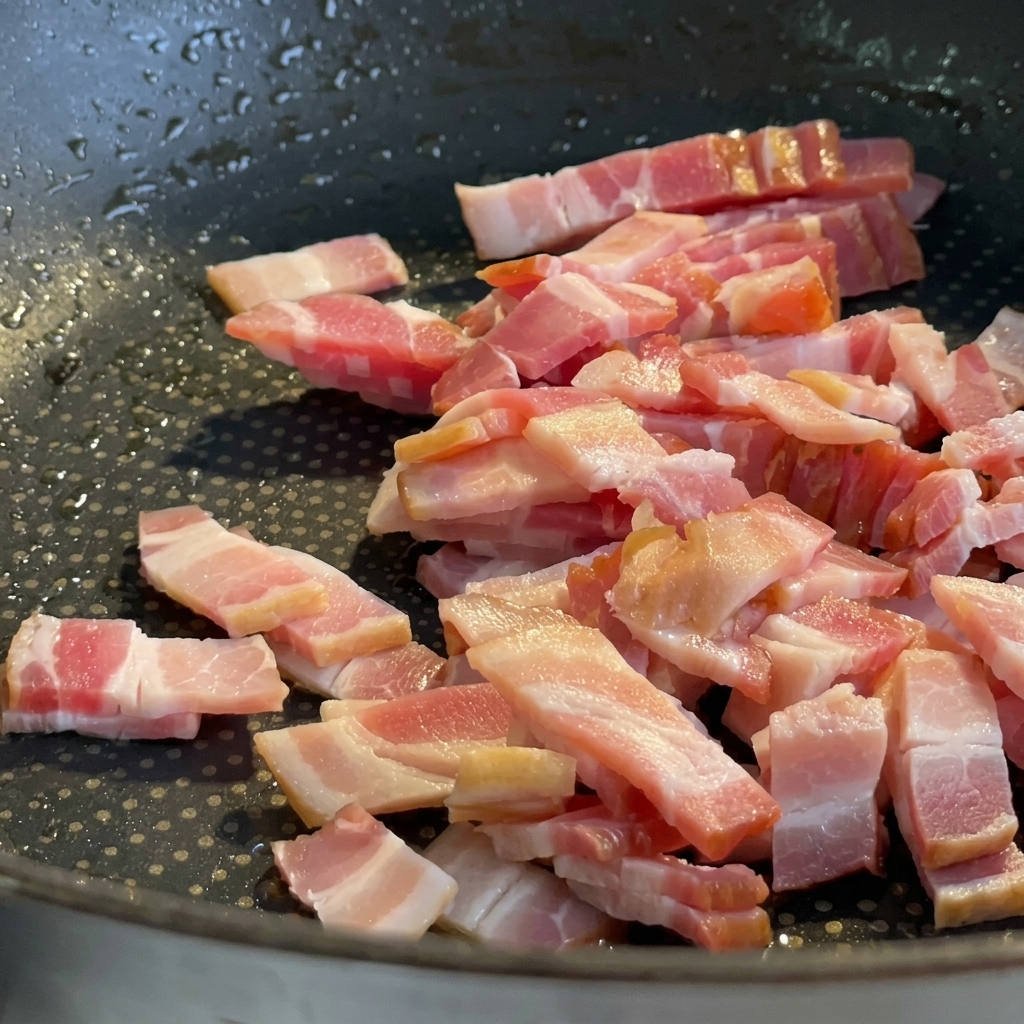 Speckwürfel braten in einer Pfanne, bis sie braun und knusprig sind.