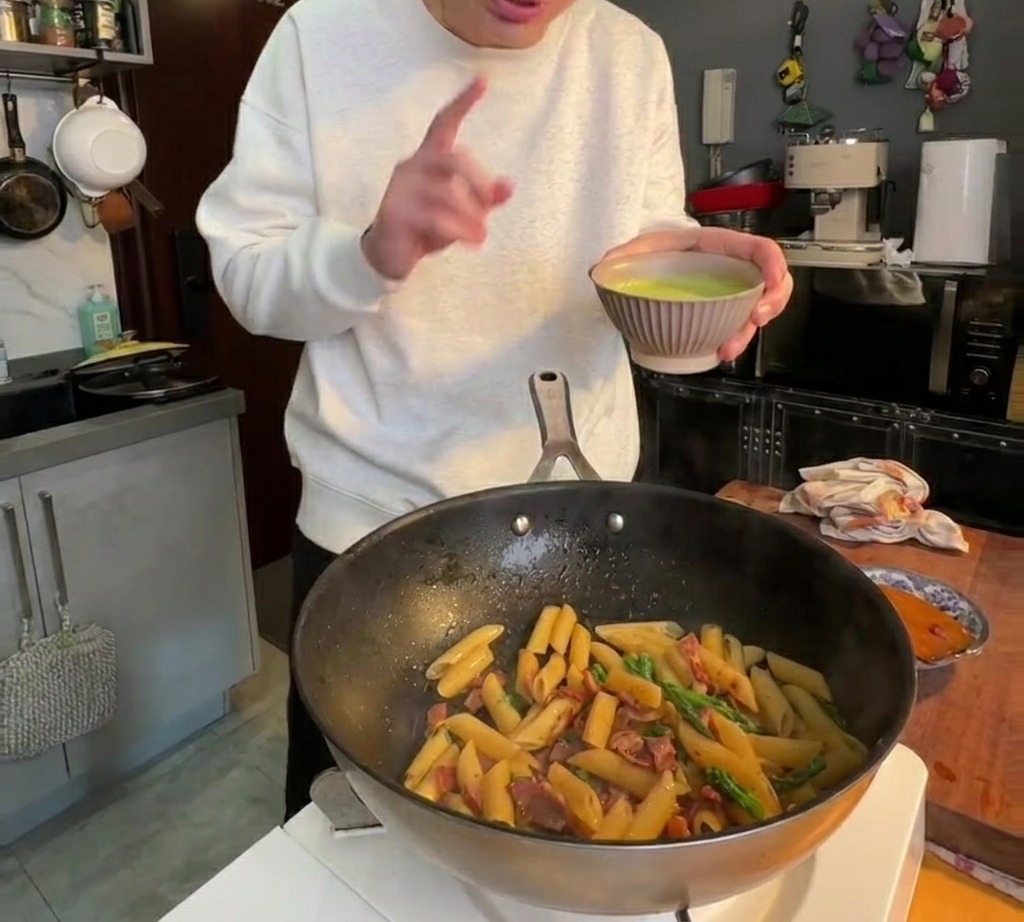 Die glatte, grüne Spargelsauce wird über die Penne-Pasta gegossen und eingerührt.