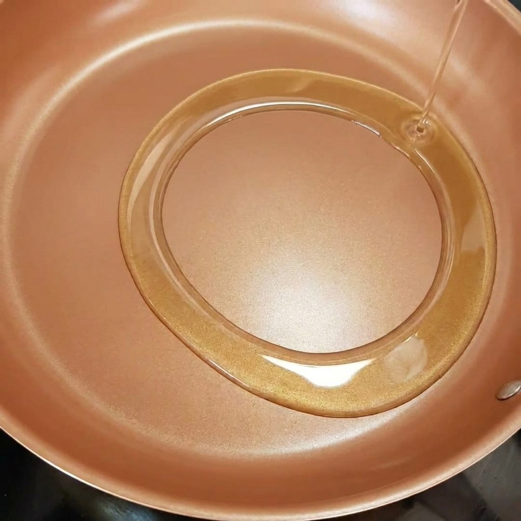 Zwiebelstreifen, die in einer Pfanne in heißem Olivenöl schmoren.
