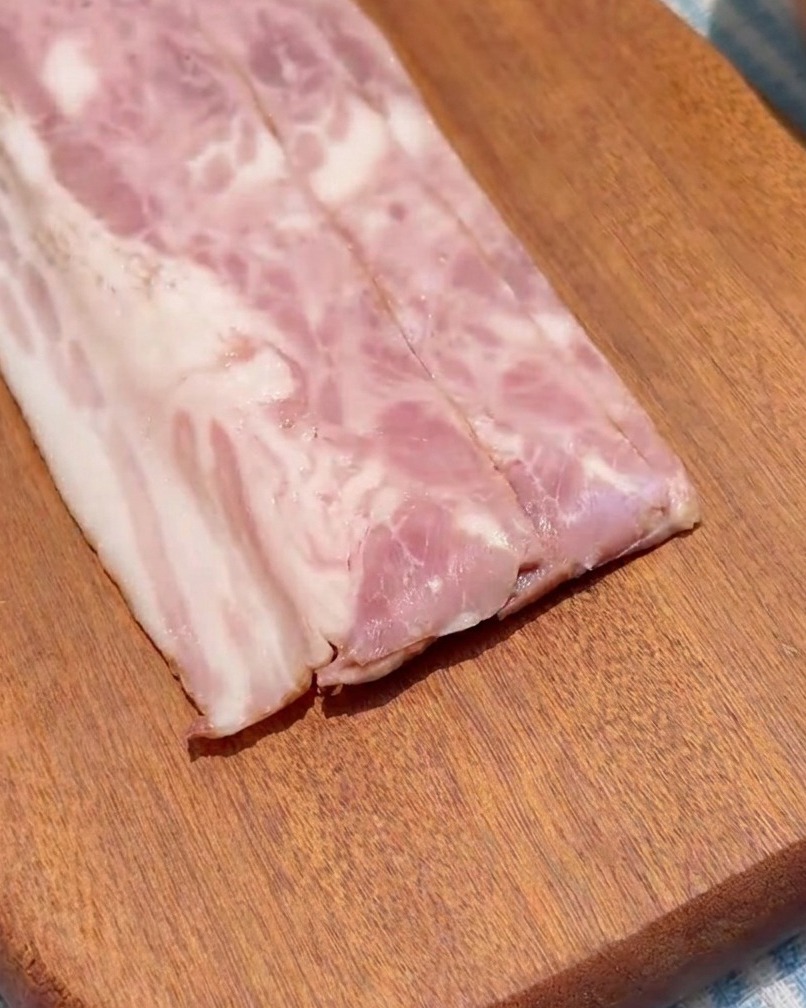 Speckstreifen werden auf einem Holzbrett in gleichmäßige Quadrate geschnitten.