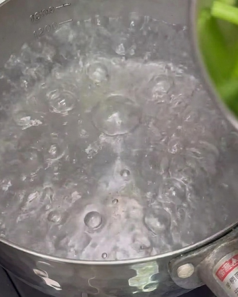 Spargelstücke kochen kurz in einem Topf mit Wasser.