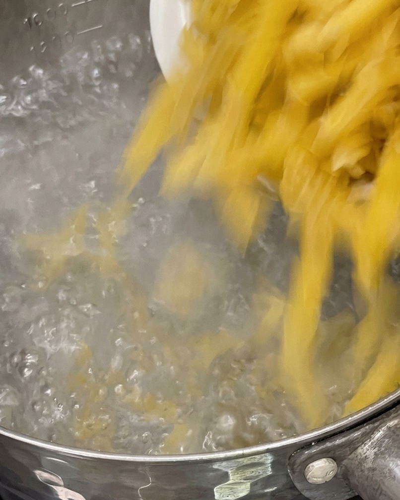 Pasta wird in einen Topf mit kochendem Wasser gegeben.