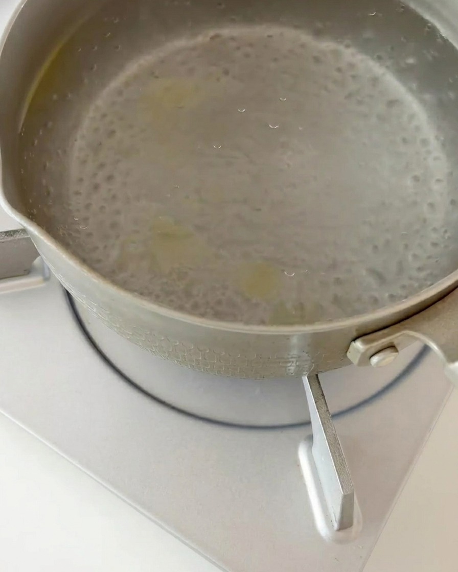 Gekochte Fusilli-Nudeln werden in einem Küchensieb aus kochendem Wasser abgegossen.