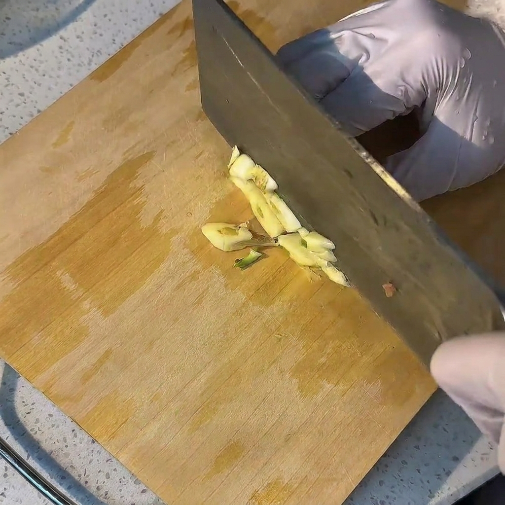 Frische Knoblauchzehen, die auf einem Holzschneidebrett fein gehackt werden.