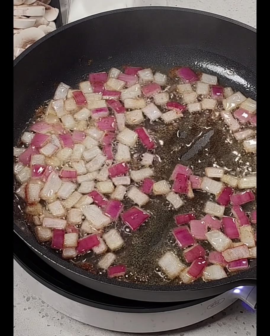 Speckstreifen werden zu den glasigen Zwiebeln in die Pfanne gegeben.