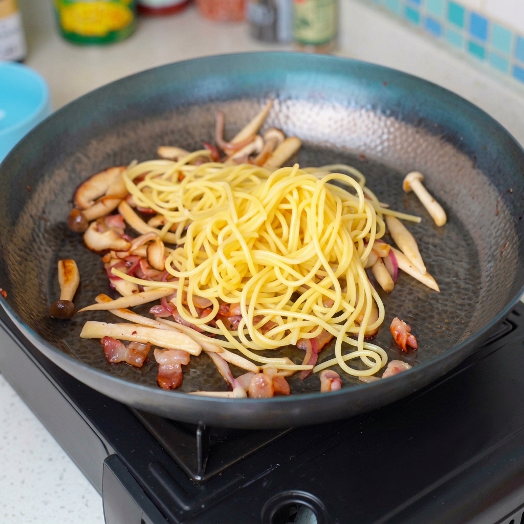 Capellini werden in die sautierten Zutaten in der Pfanne eingerührt.