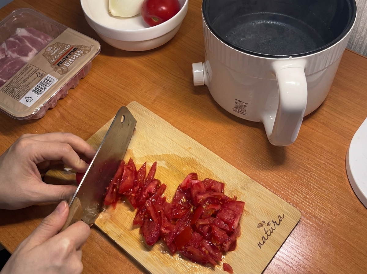 Frische rote Tomaten werden auf einem Holzschneidebrett in kleine Stücke geschnitten.