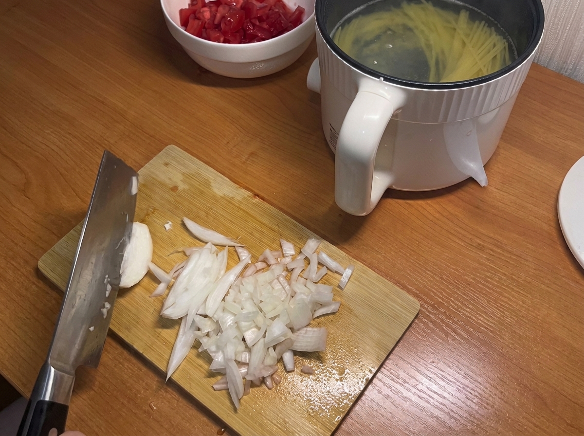 Eine weiße Zwiebel wird auf einem Schneidebrett in kleine Würfel geschnitten.