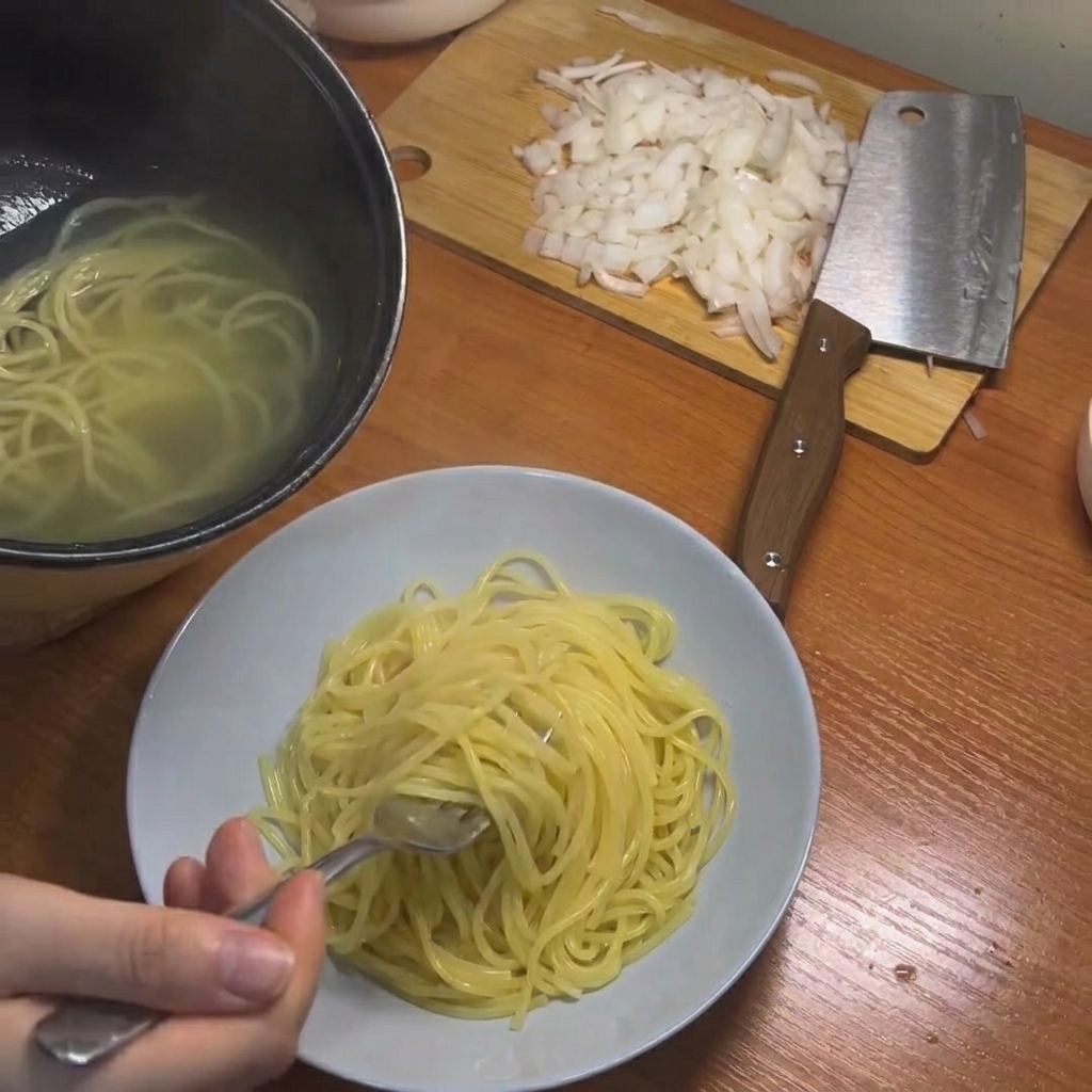 Gekochte Spaghetti werden mit Stäbchen aus dem Topf gehoben.