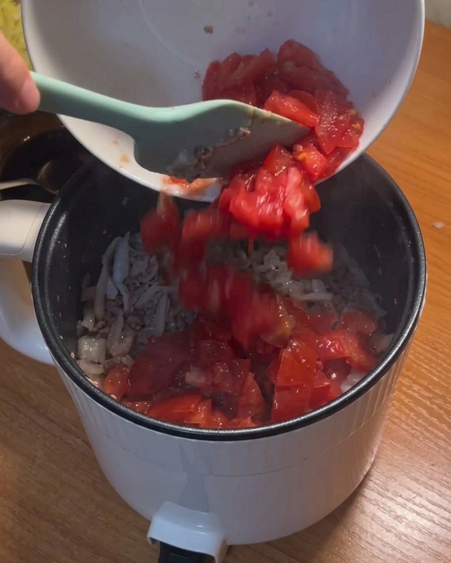 Tomatenwürfel werden aus einer Schale in den Topf gegeben.