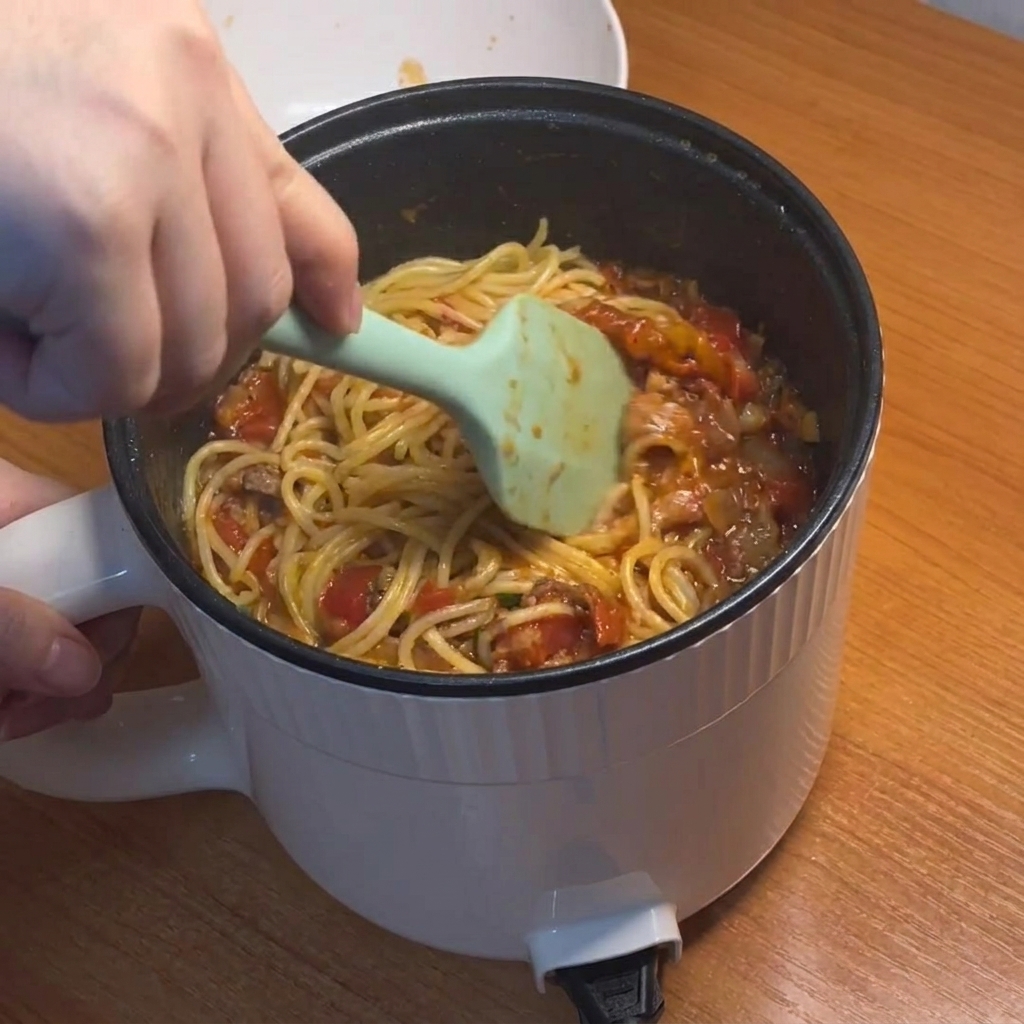 Spaghetti werden in der Sauce geschwenkt.