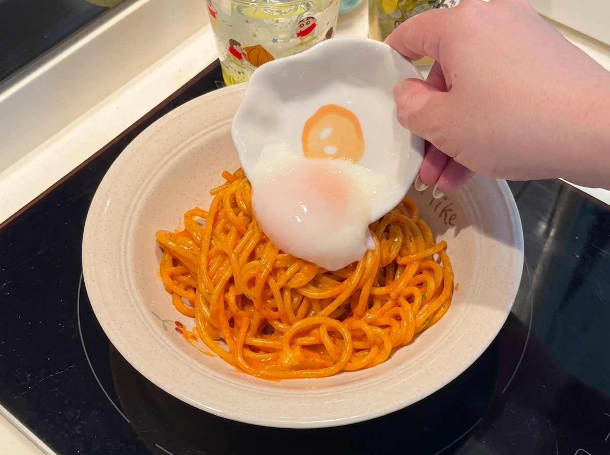 Ein weichgekochtes Ei wird auf einen Teller mit scharfen Spaghetti gelegt.