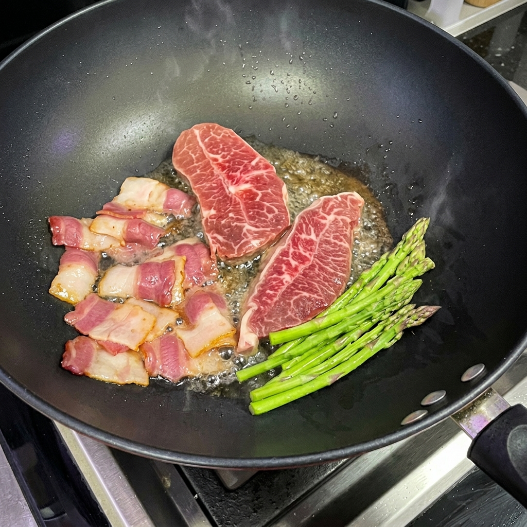 Frische grüne Spargelstangen werden neben Steak und Bacon in einem Wok gebraten.