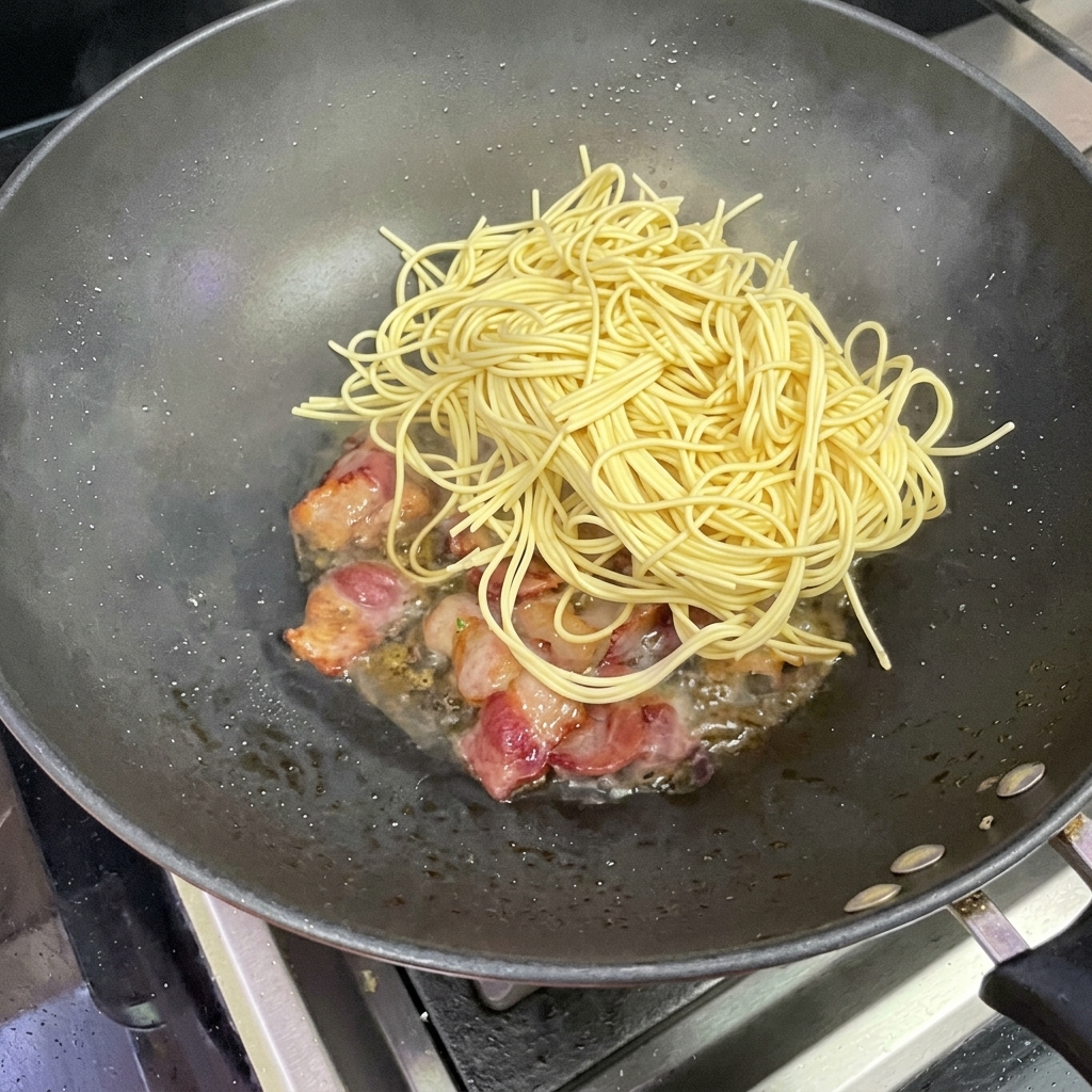 Spaghetti werden in den Wok mit Bacon gegeben.
