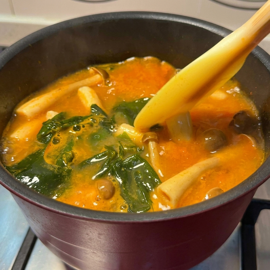 Goldbraune Lachswürfel werden in den Topf mit köchelnder Miso-Suppe gegeben.