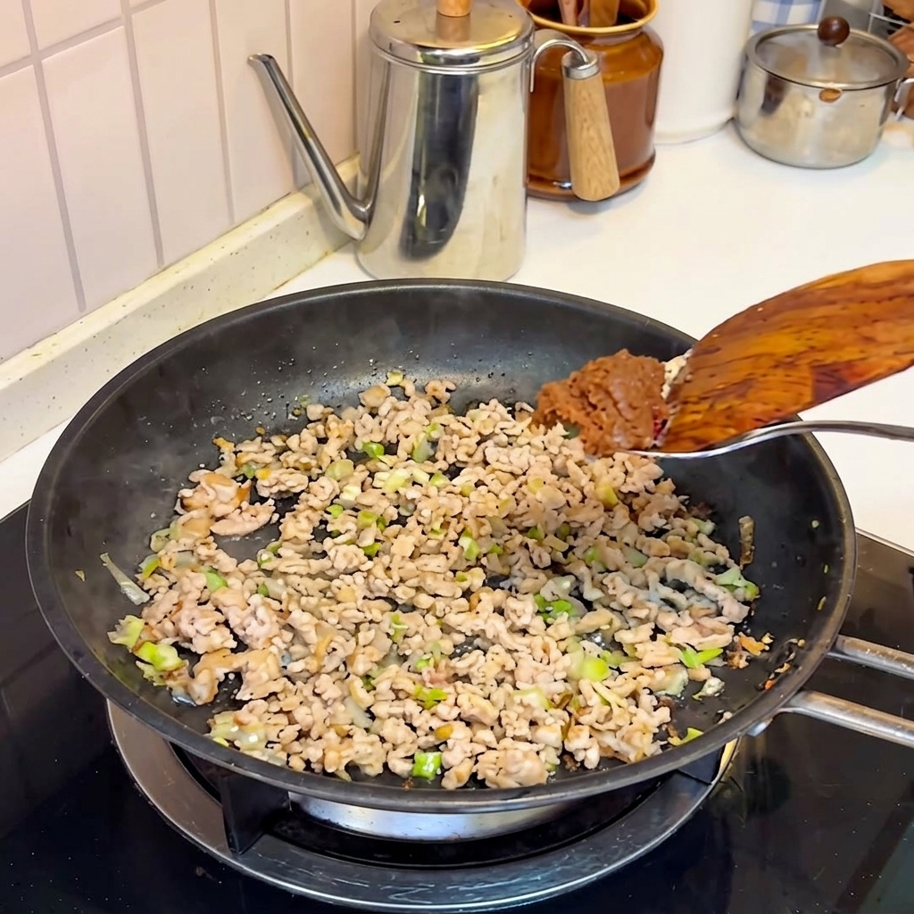 Misopaste wird zum angebratenen Fleisch in die Pfanne gegeben.