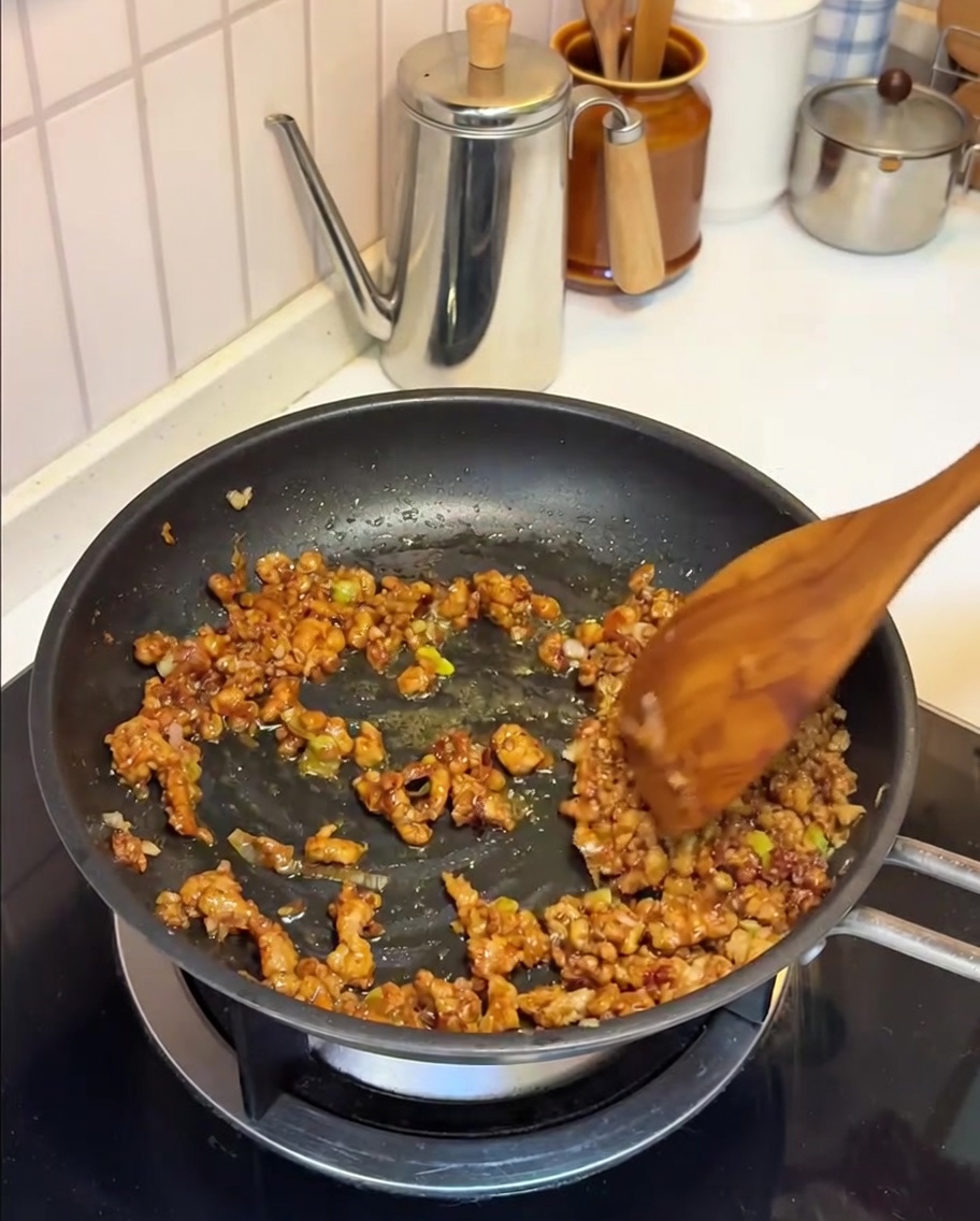 Sojamilch wird in die Pfanne zur Miso-Fleisch-Mischung gegossen.