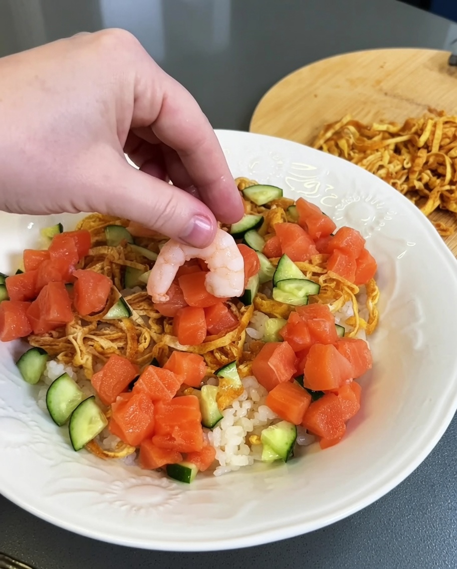 Häufchen aus frischem, gewürfeltem Lachs werden auf dem angerichteten Reis platziert.