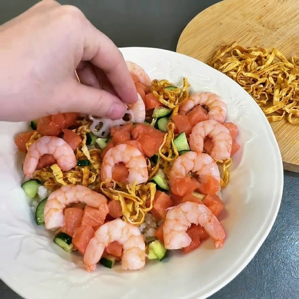 Gekochte rosa Garnelen werden vorsichtig auf dem Teller neben Lachs und Gurken angeordnet.