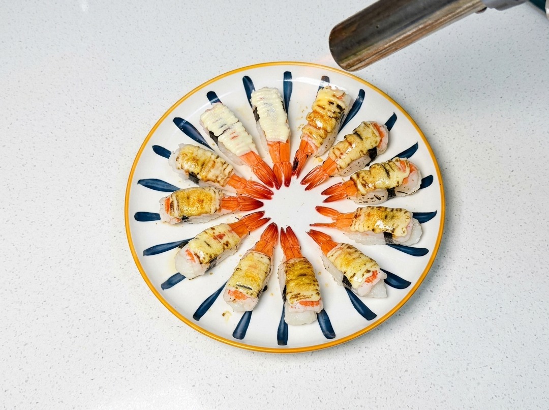 Ein Flambierbrenner bräunt den Zucker und die Mayonnaise auf dem Sushi.