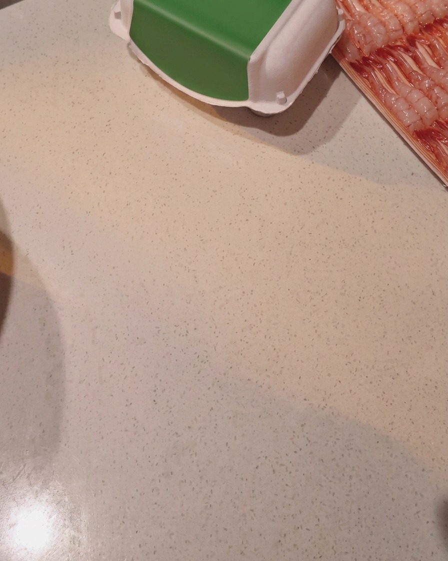 Reis wird in einem Reiskochertopf unter fließendem Wasser gewaschen.