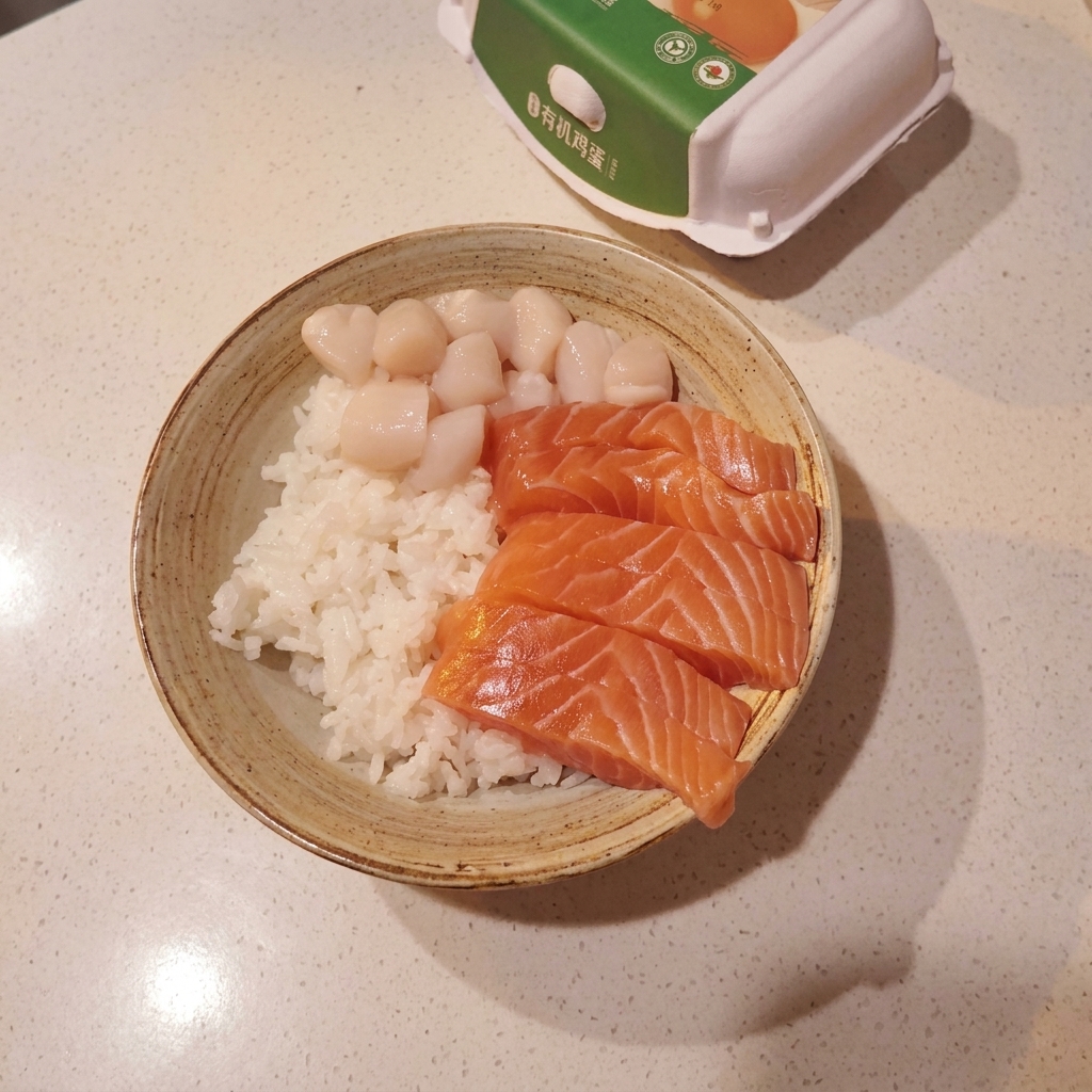 Eine Schale mit Sushireis, belegt mit einer ordentlichen Anordnung aus Lachs, Jakobsmuscheln und rohen Garnelen.